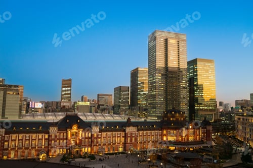 Preview: Tokyo Train Station under a clear blue sky with warm sunlight highlighting the scene.