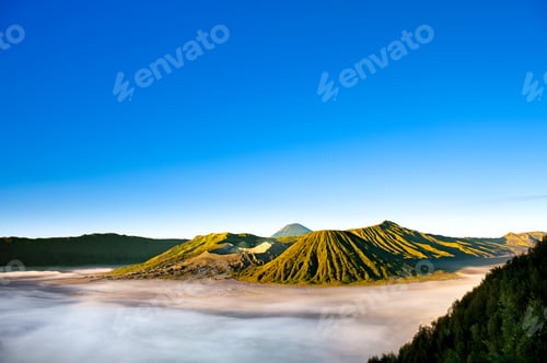 Preview: Sunrise over Mount Bromo reveals majestic volcanic ridges bathed in golden light, surrounded by mist