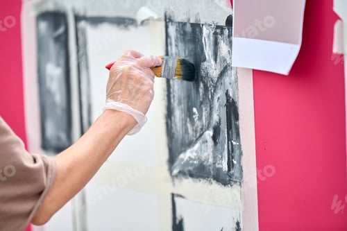 Preview: Person painting black and white abstract art on canvas near pink wall with brush and gloves