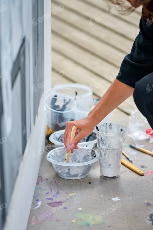 Preview: Artist mixing white paint on palette by wall with neutral wooden floor background