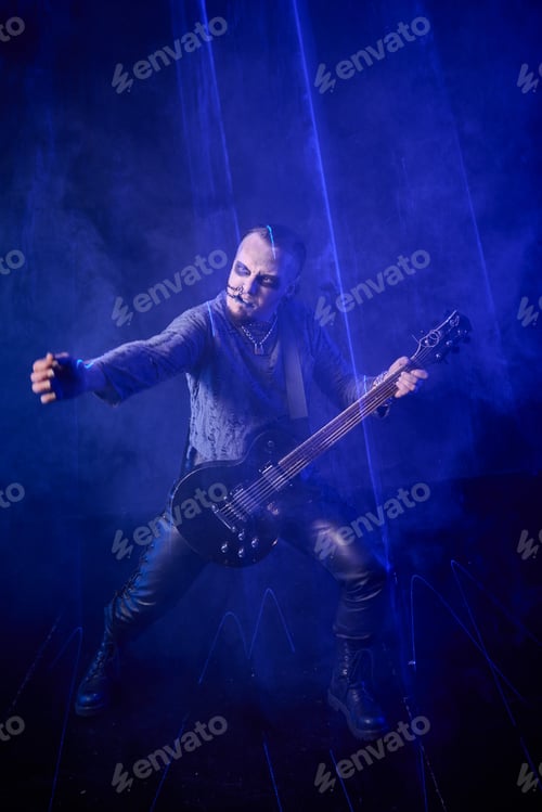 Preview: Adult male musician with mohawk playing electric guitar on dark smoky stage