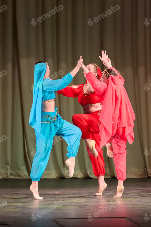 Preview: Three female dancers in colorful oriental costumes performing traditional dance on stage