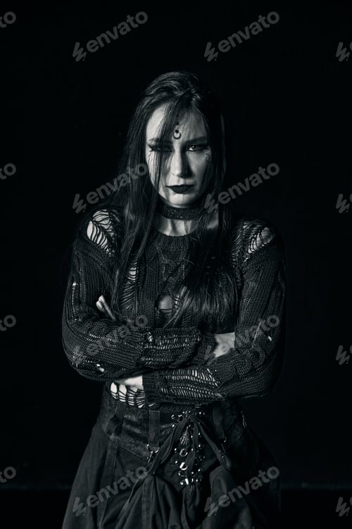 Preview: Gothic young woman with long dark hair crossing arms in dramatic low key lighting