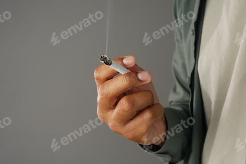 Preview: Person holds a cigarette while smoke rises in the air
