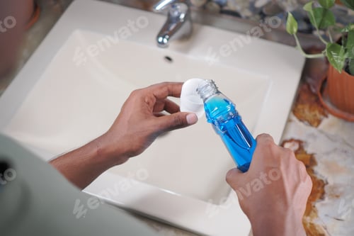 Preview: Person pours mouth wash liquid at sink