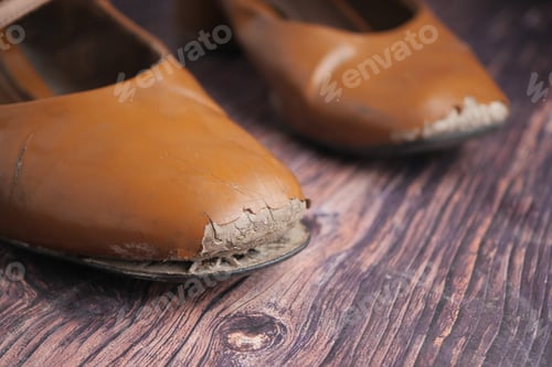 Preview: Worn brown shoes on wooden surface in soft light