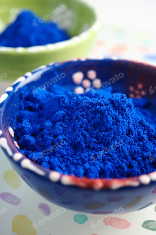Preview: Bright blue powder in a bowl with colorful background. nila powder