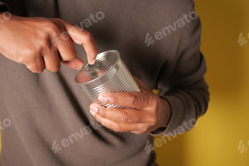 Preview: Man opens can with a can opener in a kitchen setting