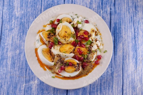 Preview: Egg dish with spices and pomegranate on a blue table