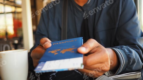 Preview: Person holds passport while sitting at a cafe table