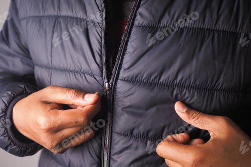 Preview: Person zipping a black jacket indoors during the day