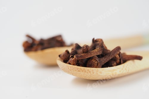 Preview: Dried cloves in wooden spoons on plain background