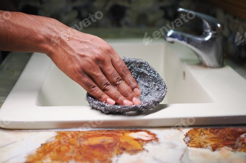 Preview: Washing dishes in a kitchen sink with a steel wool pad