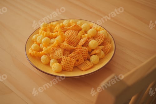Preview: Snack mix on a yellow plate sitting on a wooden table