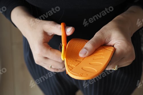 Preview: Person cuts orange shoe sole with scissors in a room