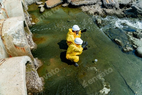 Preview: Workers collect samples near the shoreline in safety gear during daytime