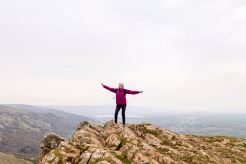 Preview: Joyful hiker atop rocky summit.