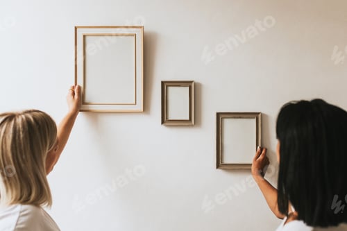 Preview: Two women styling frames on wall