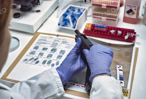 Preview: A forensic police officer examines a firearm as evidence in a homicide case at a forensic laboratory