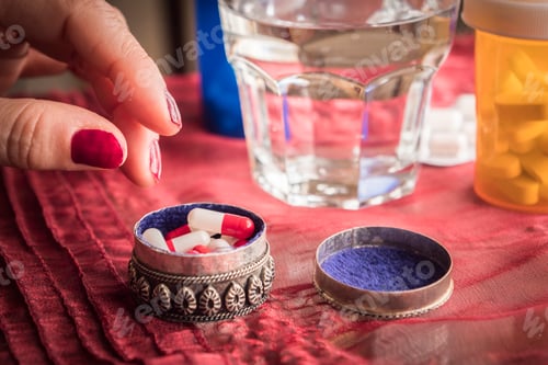 Preview: Hand women take capsules red and white in a pillbox metalic old