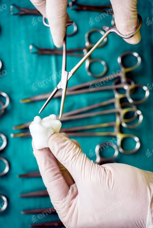 Preview: Surgeon working in operating room, hands with gloves holding scissors with torunda, conceptual image