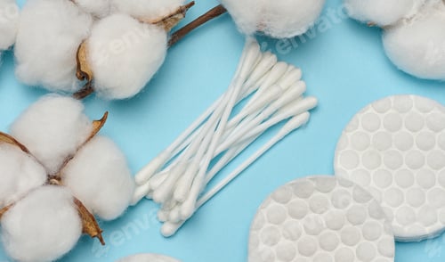 Preview: Cotton swabs, round discs and fluffy natural cotton bolls on blue background, top view