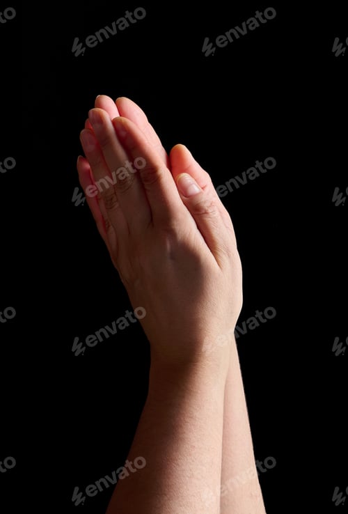 Preview: Two palms folded together in a prayer gesture on a black background symbolize faith, spiritual peace