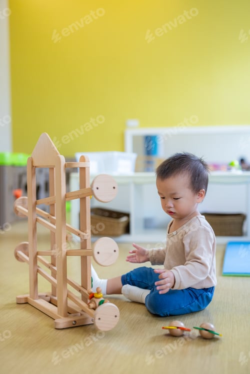 Preview: Cute asian toddler boy playing with a wooden ball ramp tracker toy