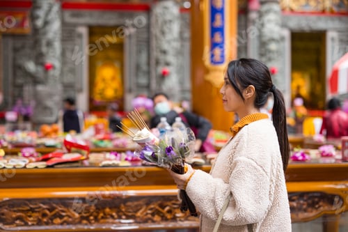 Preview: Woman lighting incense while praying in temple