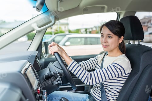 Preview: Smiling young woman driving car during day time on road trip