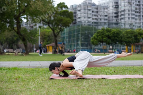 Preview: Young woman doing yoga exercise in green park outdoors