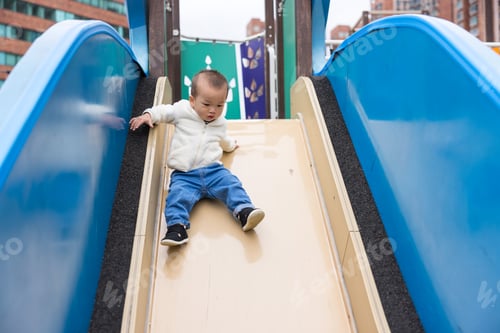 Preview: Baby boy sliding down slide at outdoor park