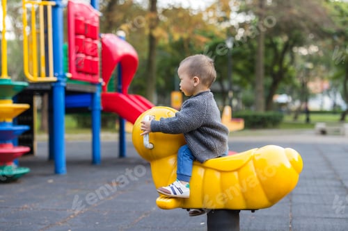 Preview: Asian toddler boy sitting on a yellow spring rider at playground