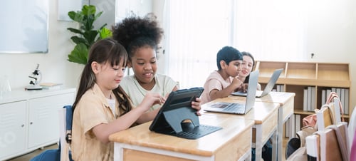 Preview: Portrait of smile two friends help elementary school children with digital tablets desks