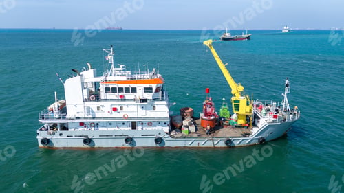 Preview: Commercial specialized vessel with a yellow crane working on a red navigational buoy in the blue oce