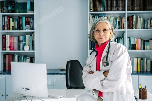 Preview: Senior female doctor sitting at her desk with confidence in her office