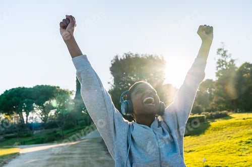 Preview: Young black woman celebrating success with arms raised