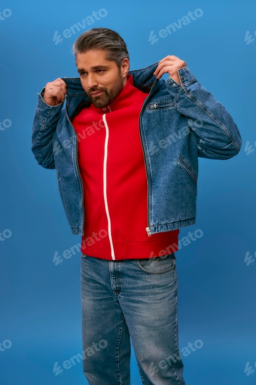 Preview: Stylish man confidently showcasing a modern denim jacket against a vibrant blue backdrop