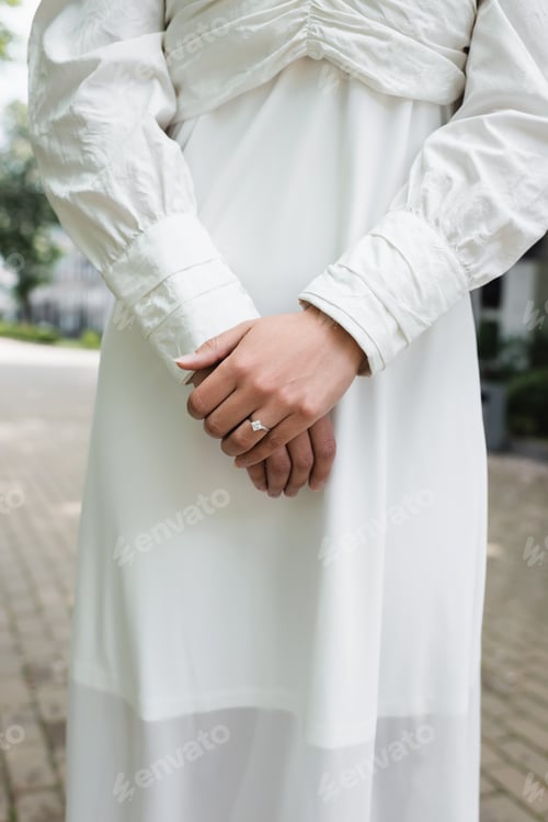 Preview: Cropped View of Bride in Wedding Dress With Diamond Ring on Finger Standing Outside