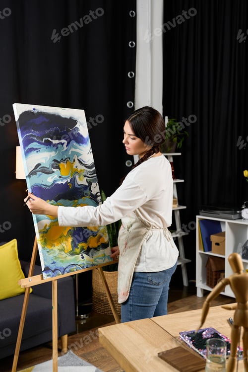 Preview: Creative young woman painting colorful art at home studio in the evening light