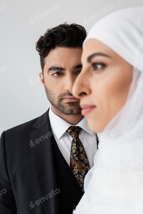Preview: Muslim man looking at blurred bride on foreground isolated on grey
