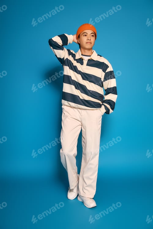 Preview: Stylish young asian man showcasing modern fashion in a vibrant studio setting