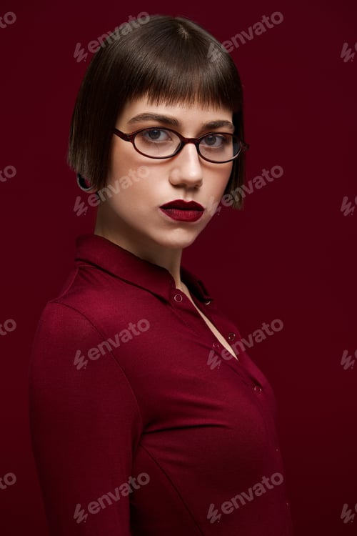 Preview: Young woman in stylish attire exudes confidence and sophistication against a rich background
