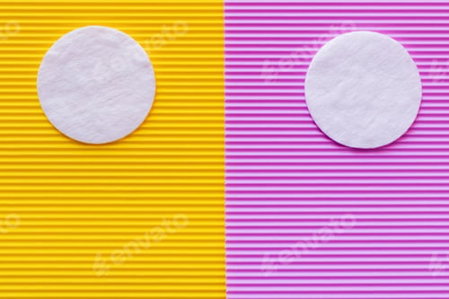 Preview: Top View of Two Cotton Pads on Purple and Yellow Textured Background