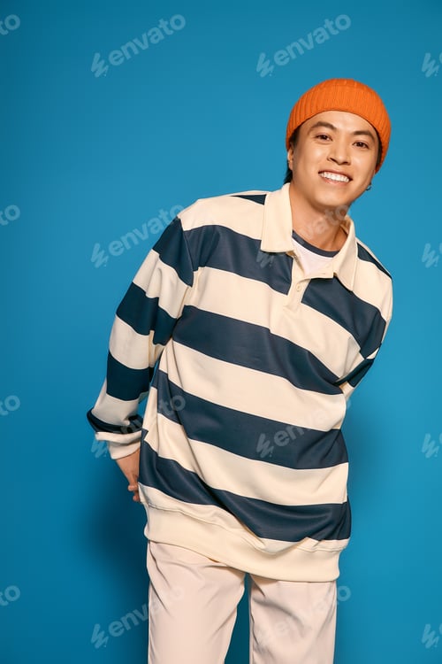 Preview: Stylish young asian man showcasing unique fashion sense in a vibrant studio setting