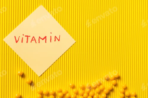 Preview: Top View of Round Shape Medication Near Paper Note With Vitamin Lettering on Yellow Textured