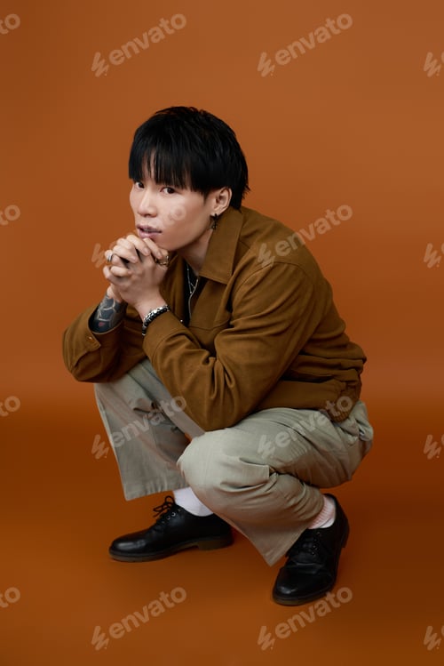 Preview: Young handsome man striking a thoughtful pose against a warm backdrop
