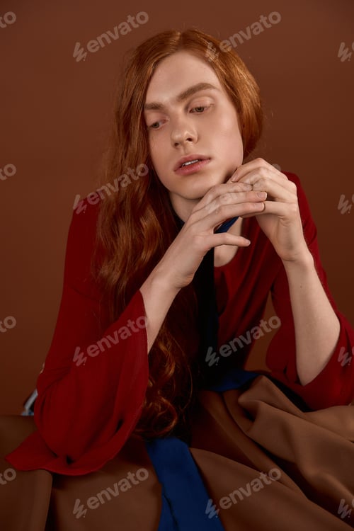 Preview: Elegant young man with long red hair showcasing fashion in a sophisticated setting