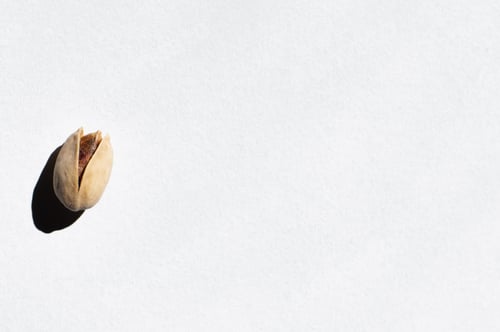 Preview: Top View of Single Cracked Pistachio Nut on White Background