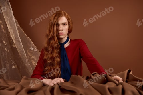 Preview: Handsome young man with long red hair showcases elegance in dramatic fashion setting